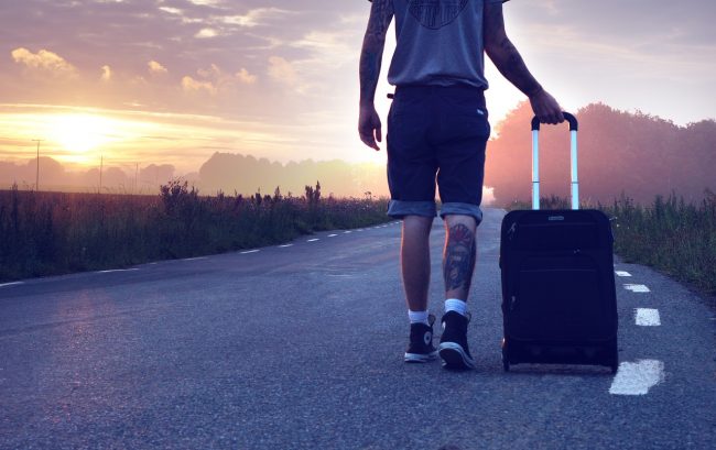 Man pulling suitcase on road